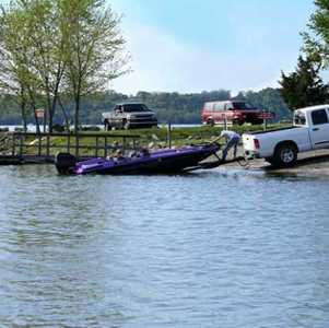 Purple boat being launched into water by a white pickup truck